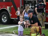 Fire fighter and little girl shooting the fire hose in front of a fire truck.